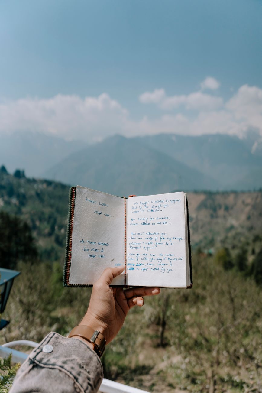 Travel author writing in a notebook overlooking mountain scenery