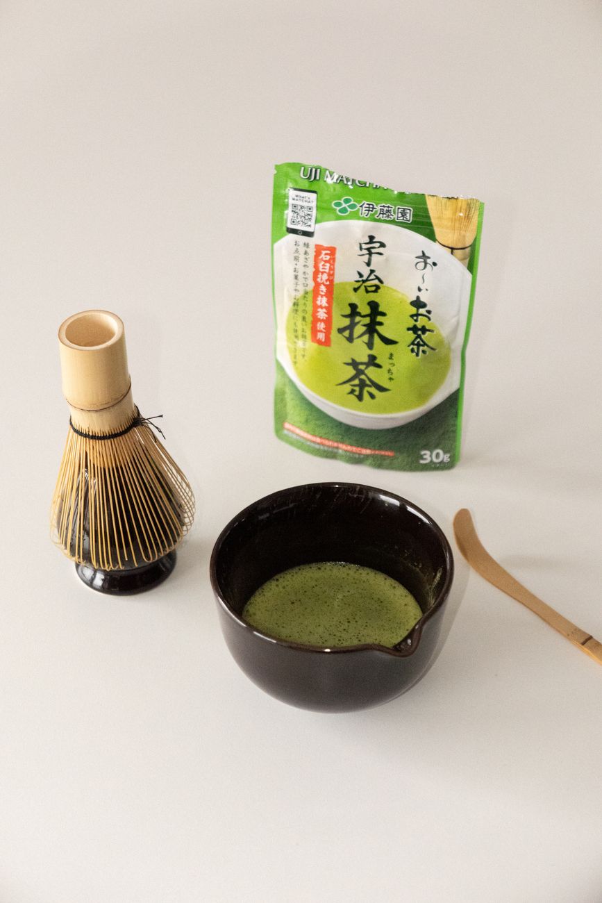 Ceremonial Japanese matcha bowl and bamboo tea whisk on wood table