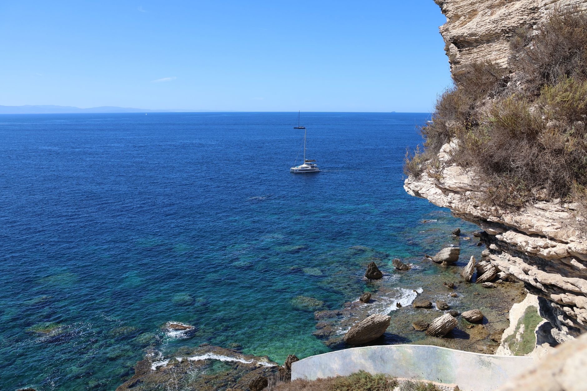 Private sailing expedition yacht near remote rocky cliffs